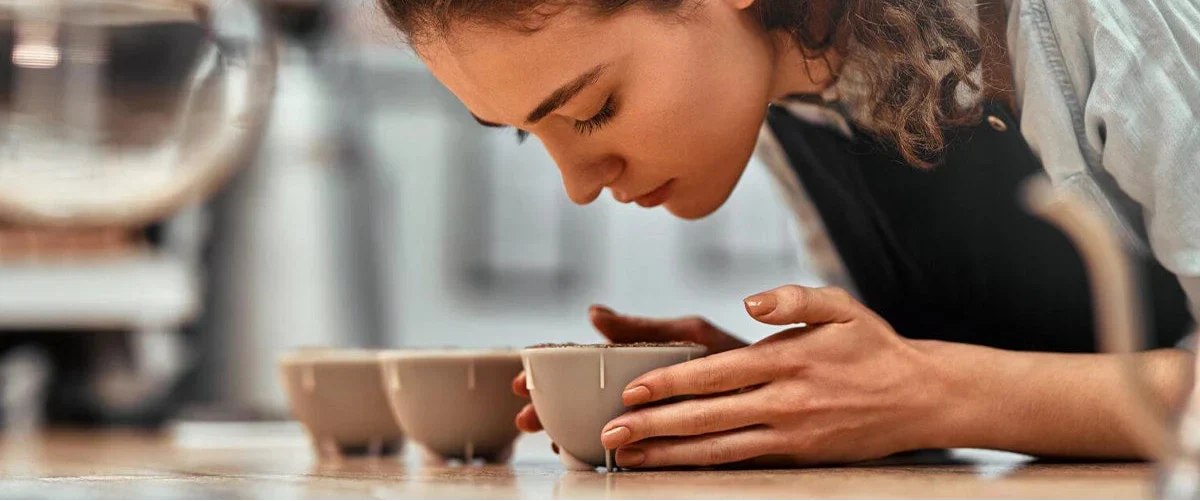 Junge Frau riecht konzentriert an Cuppingbecher – Sensorik im Kaffeeverkostungsprozess.