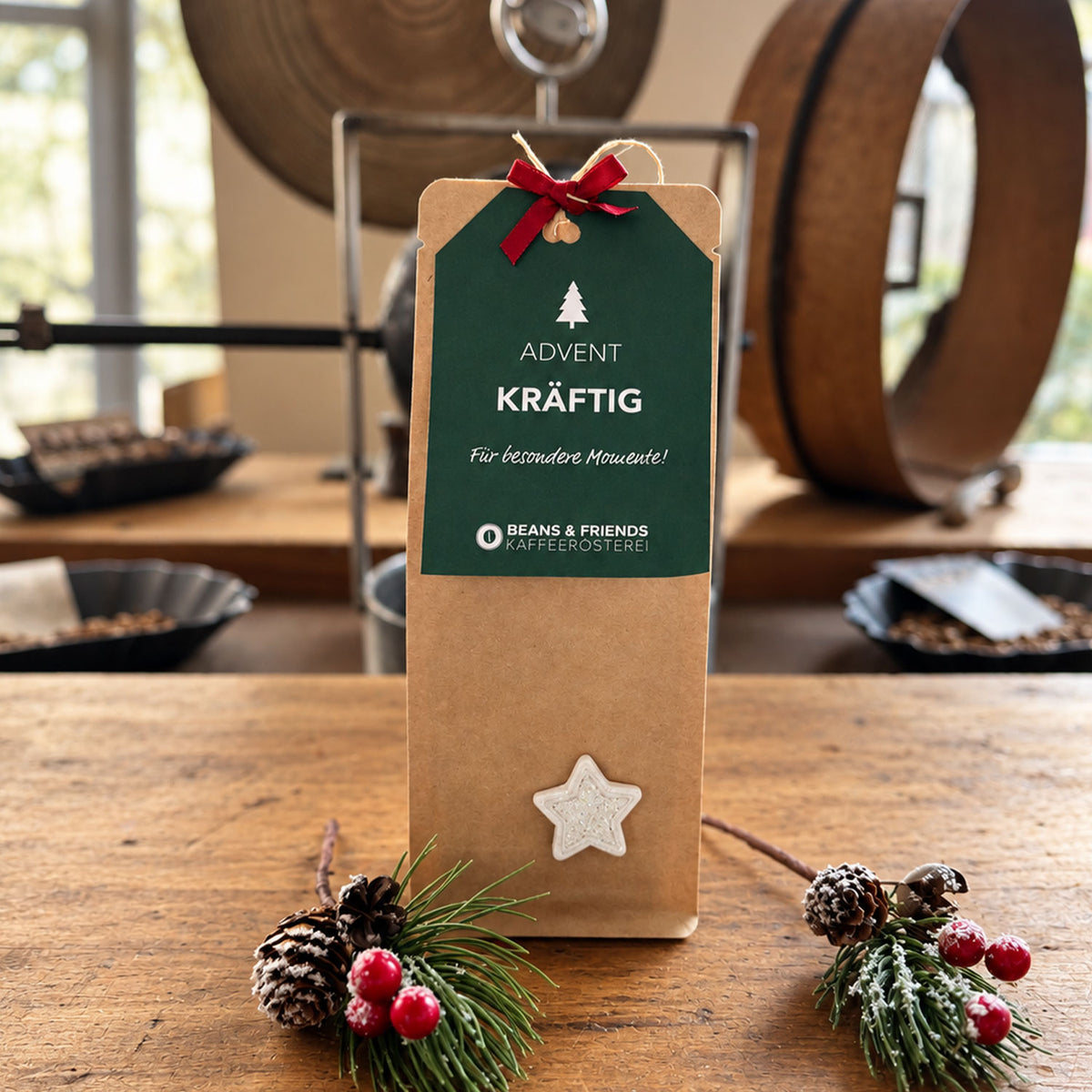 Beans & Friends Adventspaket Tassenfilter Drip Coffee mit der Geschmacksstärke kräftig in einer braunen Geschenktüte mit grünem Anhänger und Weihnachtsdekoration.