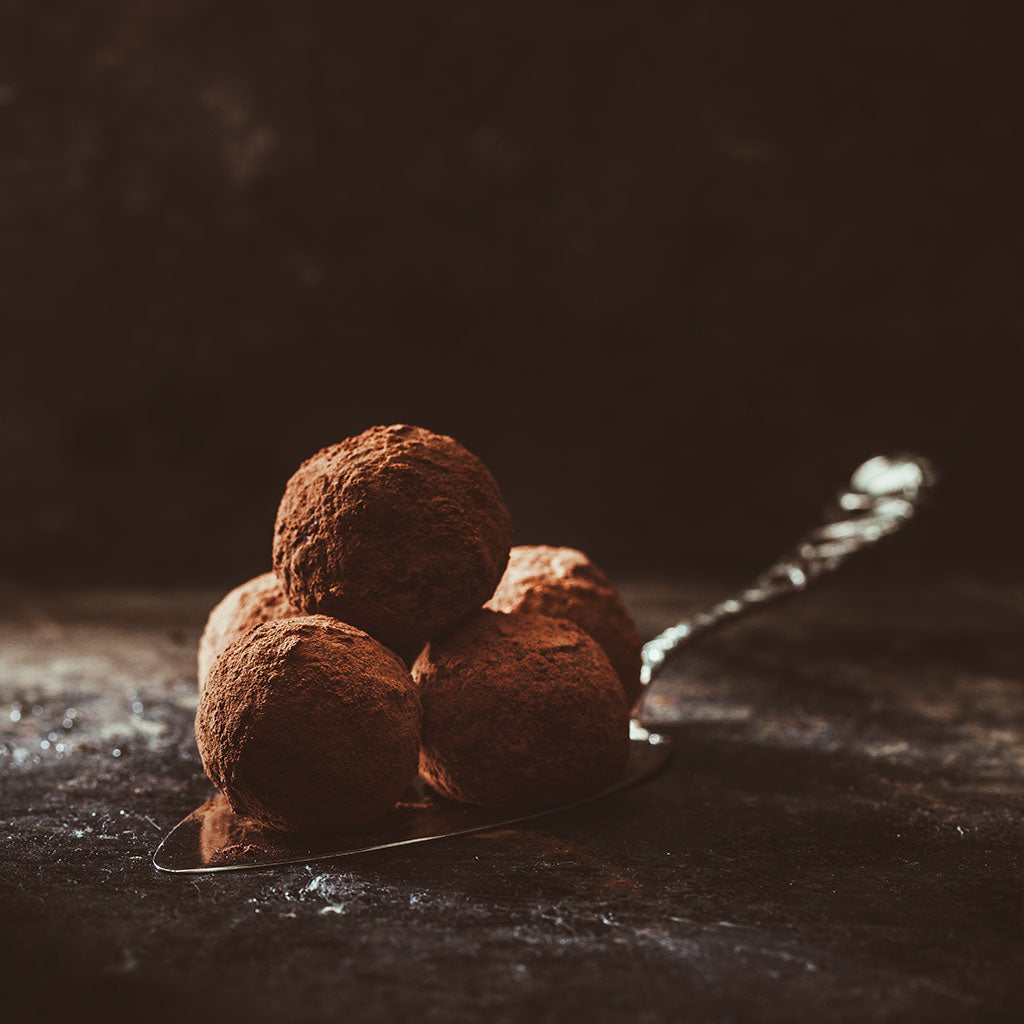 Schokoladenpralinen auf dunklem Untergrund als Sinnbild für süße, schokoladige Geschmacksnoten im Kaffee.